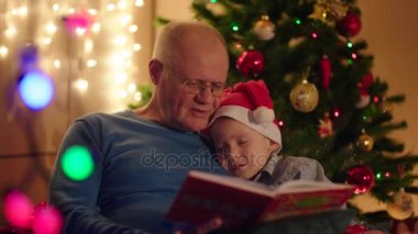 Küçük çocuk uyuyor o yeni yıl gecesi kitap okuma sırasında dedeler omzuna felling