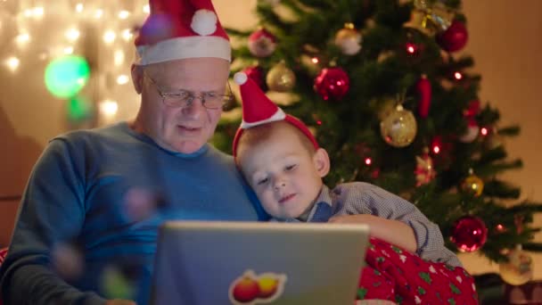 Grandpa and grandson using notebook on New Years Eve — Stock Video