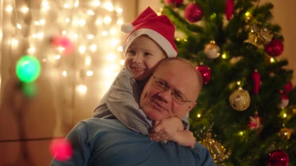 Close up portrait of little boy hugging his smiling grandpa on Christmas Eve — Stock Video