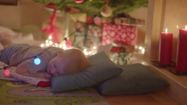아버지 크리스마스 트리 아래 선물이 한편 벽난로 근처에 크리스마스 선물에 대 한 꿈을 꾸고 그의 아들 퍼 팅 — 비디오