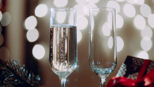 Två glas fyllning med champagne och bokeh ljus på bakgrunden — Stockvideo