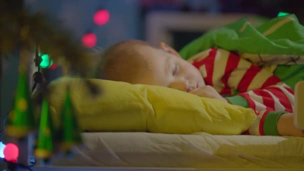Мальчик спит в своей кроватке в новогоднюю ночь. — стоковое видео