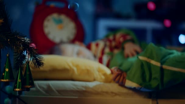 Liten pojke drömmer om gåvor i sin barnsäng på julnatten — Stockvideo