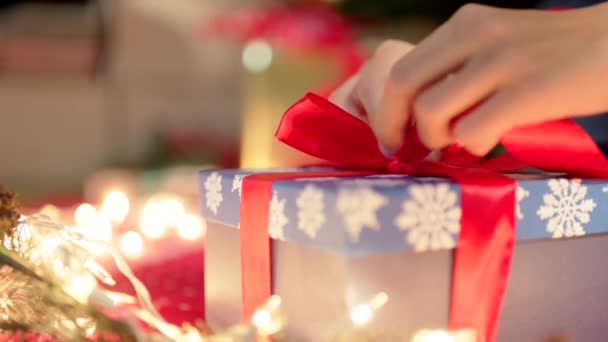 Envoltura de regalo de Navidad. Las manos atan un regalo con una cinta roja en Nochebuena — Vídeo de stock