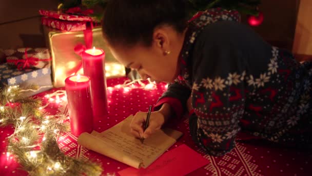 Ένα κοριτσάκι είναι ξαπλωμένη και να γράφει ένα γράμμα στον Άγιο Βασίλη — Αρχείο Βίντεο