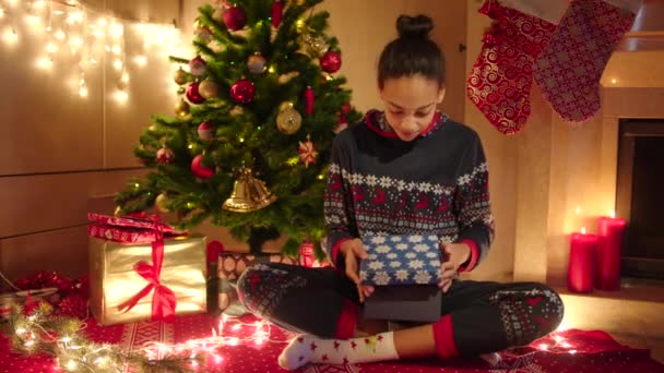 Joven mujer negra está abriendo una caja de regalo y regocijando nueva tableta en la noche de Navidad — Vídeo de stock