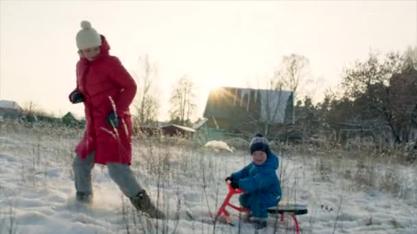 Mama i jej syn, dobra zabawa na sankach podczas zachodu słońca — Wideo stockowe