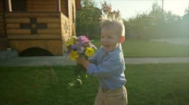 Küçük çocuk annesine çiçek demet ile günbatımında çalışan.