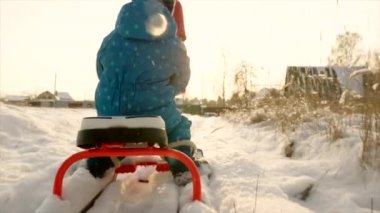 Anne küçük oğlu kızağa kış yürüyüş sırasında gün batımında haddeleme