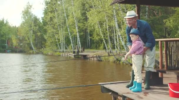 Liten pojke och hans farfar på fiske vid sjön — Stockvideo