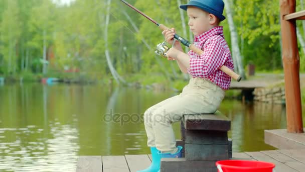 Niño en sombrero de paja con spinning en la pesca de agua dulce en el lago — Vídeo de stock