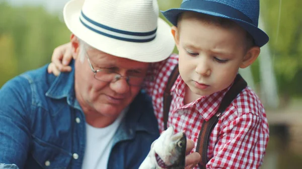 Onun küçük boy gülümseyerek portresi ilk yaz tatillerini büyükbabası ile tatlı su balık üzerinde somon balığı yakalamak