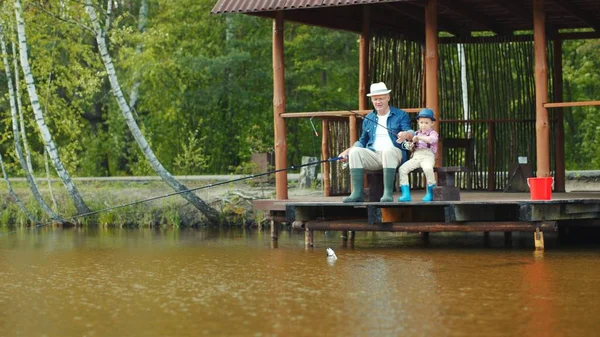 Niño y su abuelo la captura de salmón en la pesca de agua dulce en el lago — Foto de Stock
