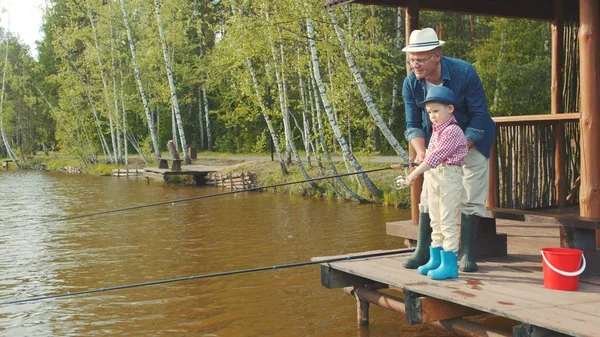 Mały chłopiec i jego dziadek połowu łososia na połowy ryb słodkowodnych, nad jeziorem — Zdjęcie stockowe