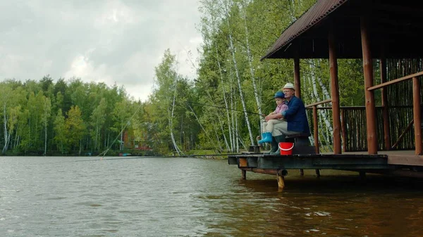 Niño y su abuelo la captura de salmón en la pesca de agua dulce en el lago — Foto de Stock