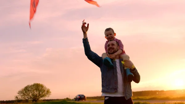 Malý chlapec a jeho otec hrál létání draka v parku při západu slunce — Stock fotografie