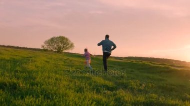 Baba ve küçük oğlu uçan uçurtma günbatımında oynuyorlar