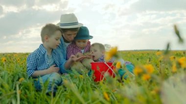 Anne küçük oğulları ile oynuyor ve onlar çim alan oturuyorlar