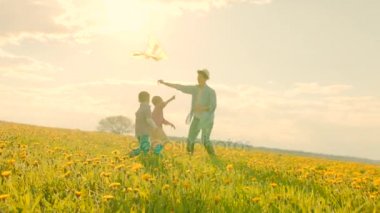 Gün batımında annesiyle oynayan küçük çocuklar uçan uçurtma