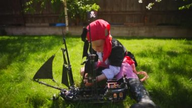 Korsan kostüm giyen küçük çocuk oyuncak gemi Karayip Korsanları'nın bahçesinde, Cadılar Bayramı'nda oynuyor