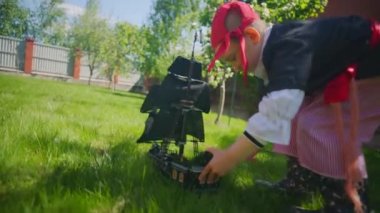 Korsan kostüm giyen küçük çocuk oyuncak gemi Karayip Korsanları'nın bahçesinde, Cadılar Bayramı'nda oynuyor