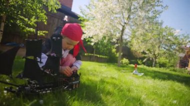 Korsan kostüm giyen küçük çocuk oyuncak gemi Karayip Korsanları'nın bahçesinde, Cadılar Bayramı'nda oynuyor