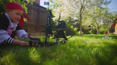 Korsan kostüm giyen küçük çocuk oyuncak gemi Karayip Korsanları'nın bahçesinde, Cadılar Bayramı'nda oynuyor