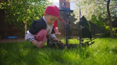 Korsan kostüm giyen küçük çocuk oyuncak gemi Karayip Korsanları'nın bahçesinde, Cadılar Bayramı'nda oynuyor