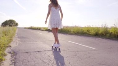 Genç güzel kadın kaykay üzerinde ülke yolda gün batımında buz pateni