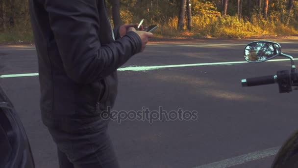 Biker está fumando e usando telefone na beira da estrada durante a viagem de carro — Vídeo de Stock