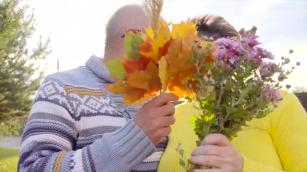 Casal sênior está beijando e fechando seu rosto com um buquê de flores — Vídeo de Stock