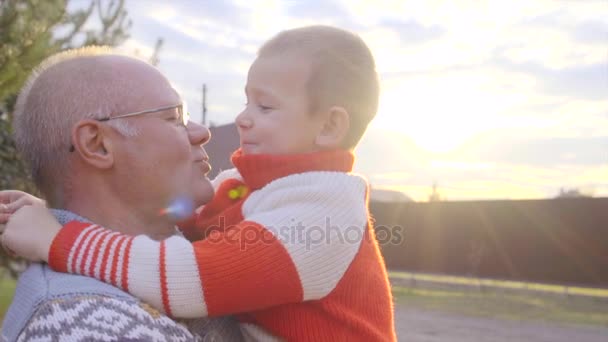 Enkel in den Armen seines Großvaters bei Sonnenuntergang — Stockvideo
