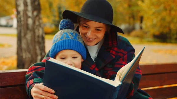 Malý chlapec a jeho matka se dívají rodinné album na podzim park — Stock fotografie