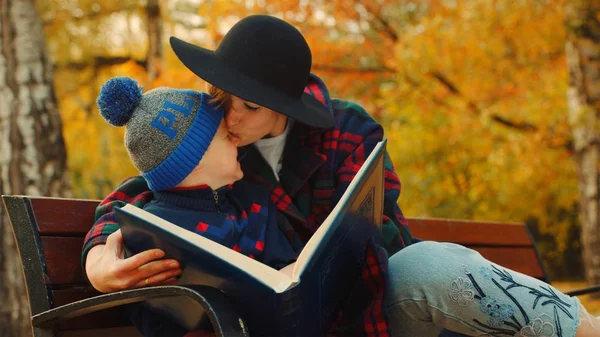 Madre está besando a su hijo en el parque de otoño —  Fotos de Stock