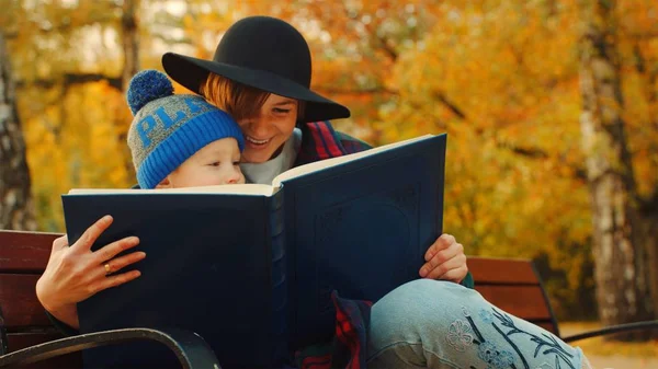 Kleiner Junge und seine Mutter schauen Familienalbum im Herbstpark — Stockfoto