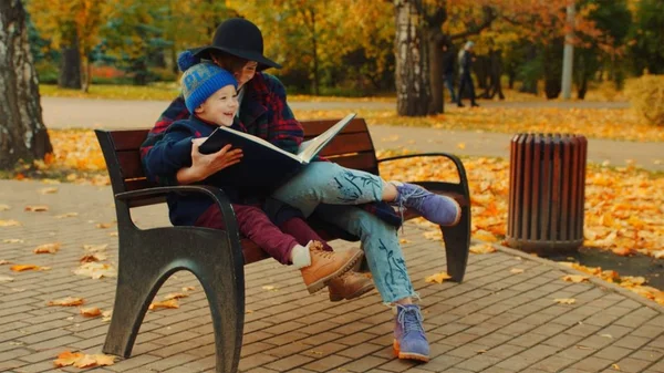 少年と彼の母親は、秋の公園での家族のアルバムを見ています。 — ストック写真