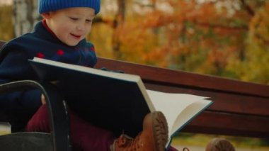 Küçük çocuk sonbahar parkta büyük aile albümü izliyor