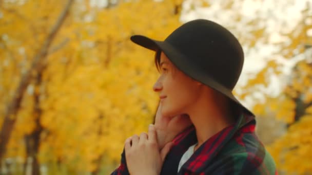 Mujer joven está hablando con alguien por teléfono mientras se pasea en el parque de otoño — Vídeo de stock