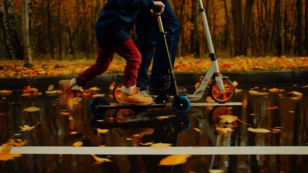 Niño y su abuelo están montando patinetas juntos en el parque de otoño —  Fotos de Stock