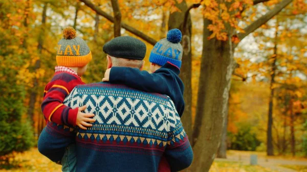 İki küçük çocuklar ve onların dedesi sonbahar parkta