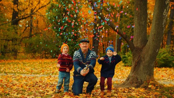 祖父は孫と秋の公園でパーティー クラッカーを爆発します。 — ストック写真