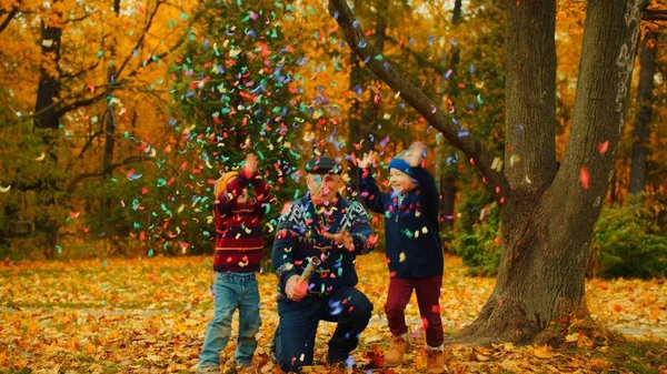 Dědeček je vybuchující strana cracker v podzimním parku s jeho vnuků — Stock fotografie