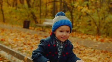 Küçük mutlu çocuk sonbahar parkta tekme scooter sürme