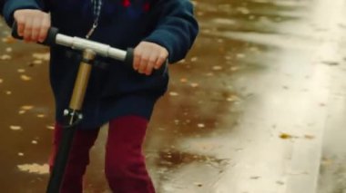 Küçük mutlu çocuk sonbahar parkta tekme scooter sürme