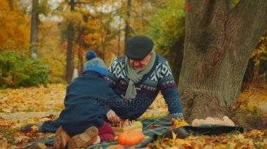 Küçük çocuk ile dedesi büyük ağacın altında sonbahar parkta satranç oynuyor