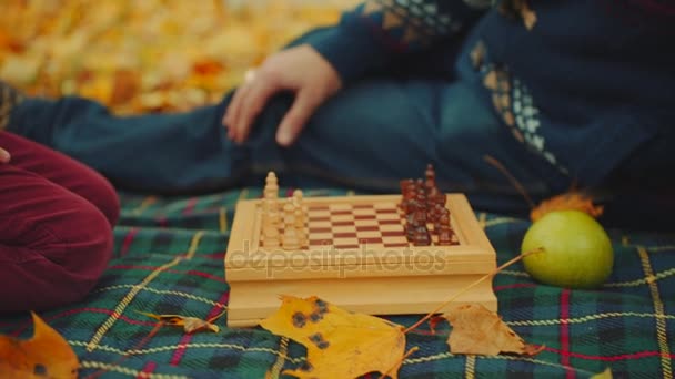 Дедушка учит внуков играть в шахматы в осеннем парке. — стоковое видео