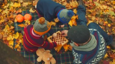 Dedesi sonbahar parkta satranç oynamak için onun torunları öğretiyor