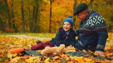 Küçük bir çocuk ve onun dedesi sonbahar parkta