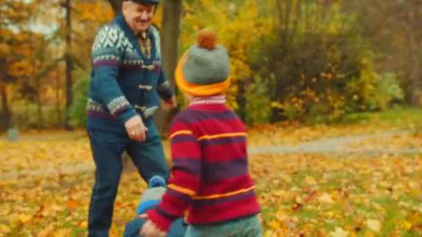 Il nonno sta facendo due chiacchiere con i nipoti nel parco autunnale. — Video Stock