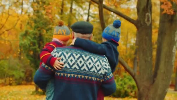 Abuelo con nietos en la mano en el parque de otoño — Vídeos de Stock